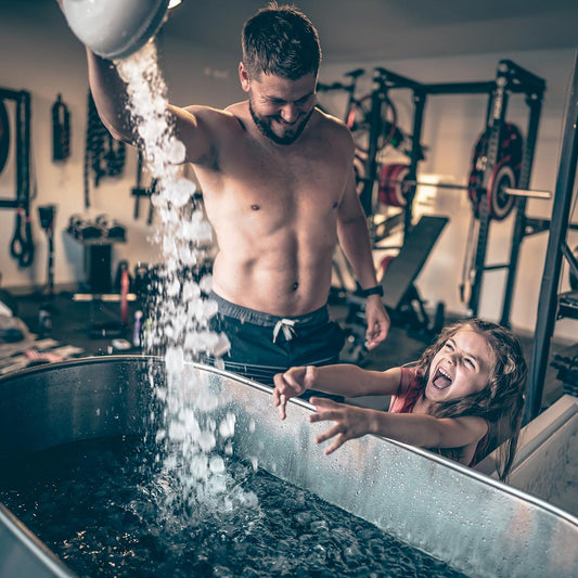 A male athlete pours ice into a cold tank to prepare for an ice bath to aid in exercise muscle recovery